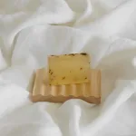 Handmade soap on wooden dish, white fabric background.