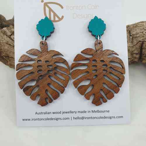 Womens Monstera leaf earrings made from queensland walnut and paired with an aqua blue post.
