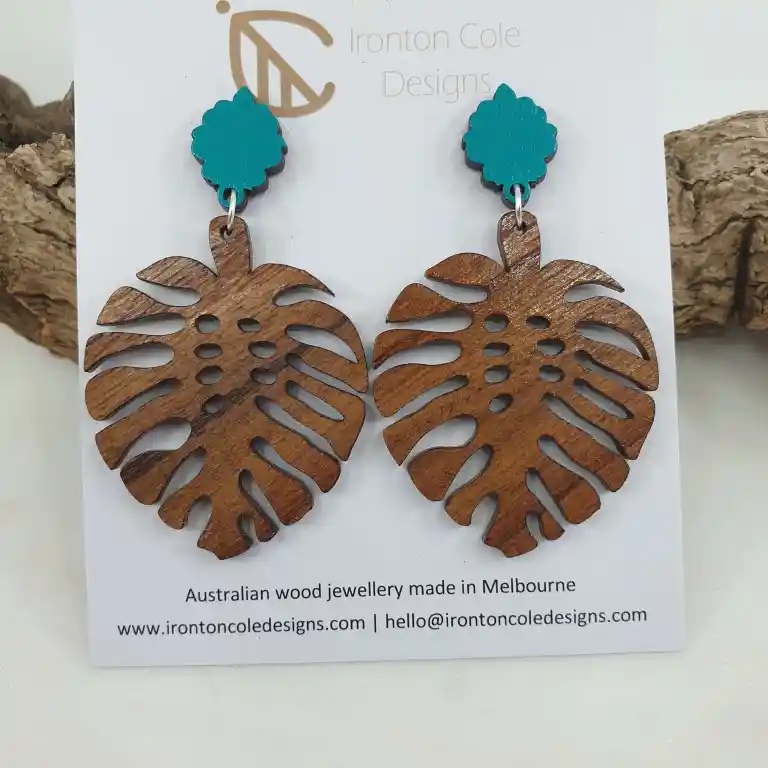 Womens Monstera leaf earrings made from queensland walnut and paired with an aqua blue post.