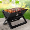 Portable BBQ with grilled meat and veggies outdoors.