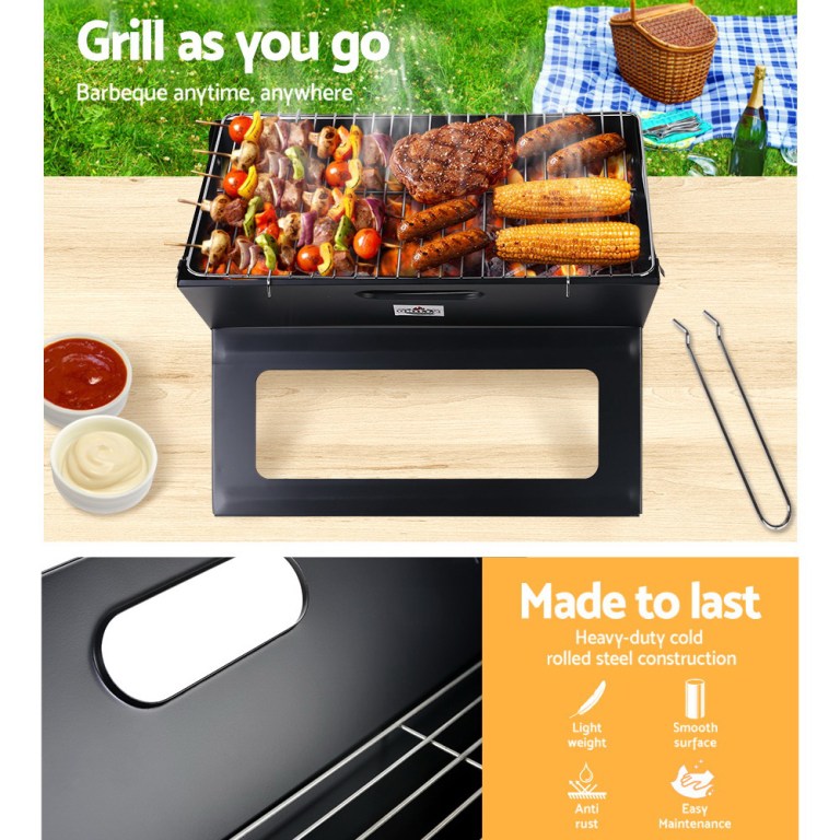Portable BBQ grill with skewers and corn, picnic ready.