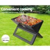 Portable BBQ with grilled food on lush lawn