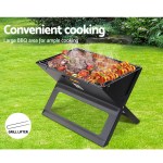 Portable BBQ with grilled food on lush lawn