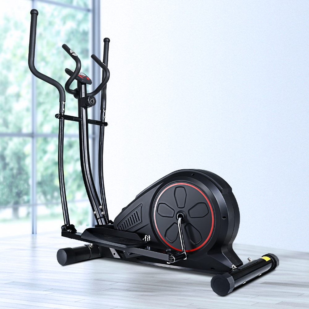Black elliptical machine by window on wooden floor.