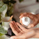 Hands applying lotion from pump bottle