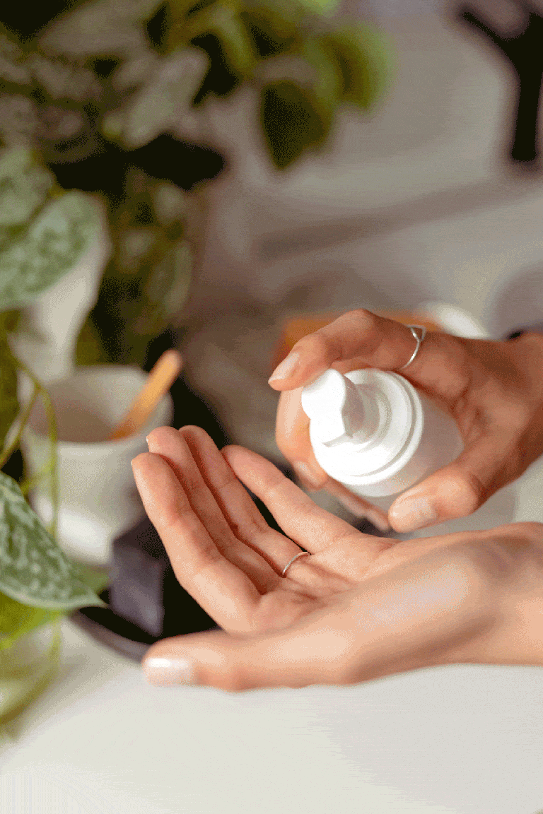 Hands applying lotion from pump bottle