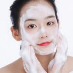Woman applying foaming facial cleanser.