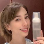 Person holding a clear skincare product bottle.