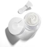 Open jar of white face cream with applicator.