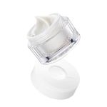 Luxury skincare cream in clear jar, lid open.