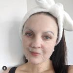 Woman wearing sheet mask and headband.