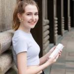 emulsion spray | triple action | super moisturizing | acne & spot removal Woman smiling, holding a water bottle outdoors.