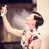 Woman using facial mist spray indoors