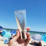Person holding sunscreen at sunny beach