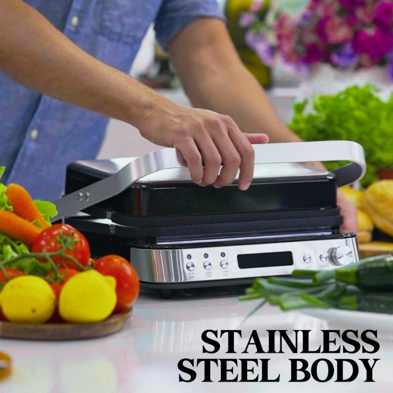 Person using stainless steel sandwich press in kitchen.