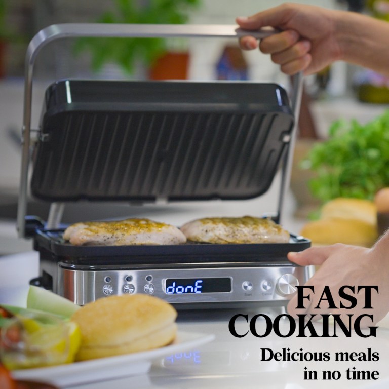Electric grill cooking seasoned chicken fillets indoors.