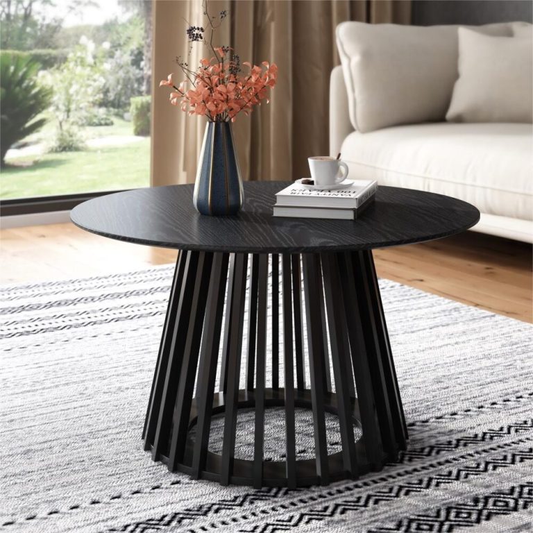 Modern round table with vase, books, and mug.