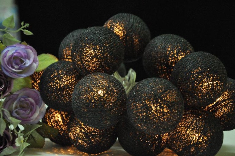 Illuminated black string lights next to purple flowers.