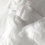 White quilt and pillow with buttons for fastening.