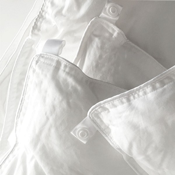 White quilt and pillow with buttons for fastening.