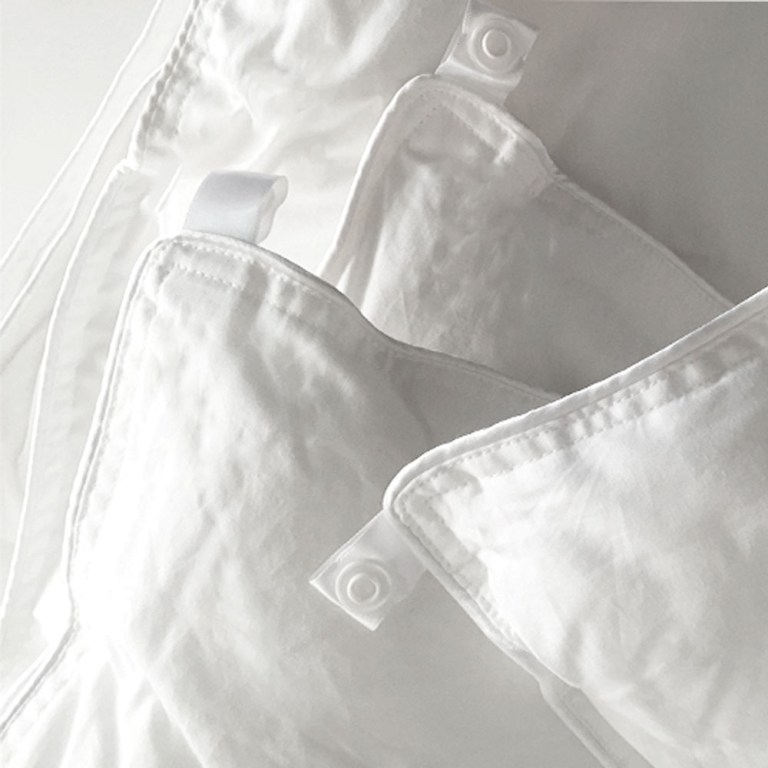 White quilt and pillow with buttons for fastening.