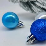 Closeup of blue and silver Christmas baubles on fabric.