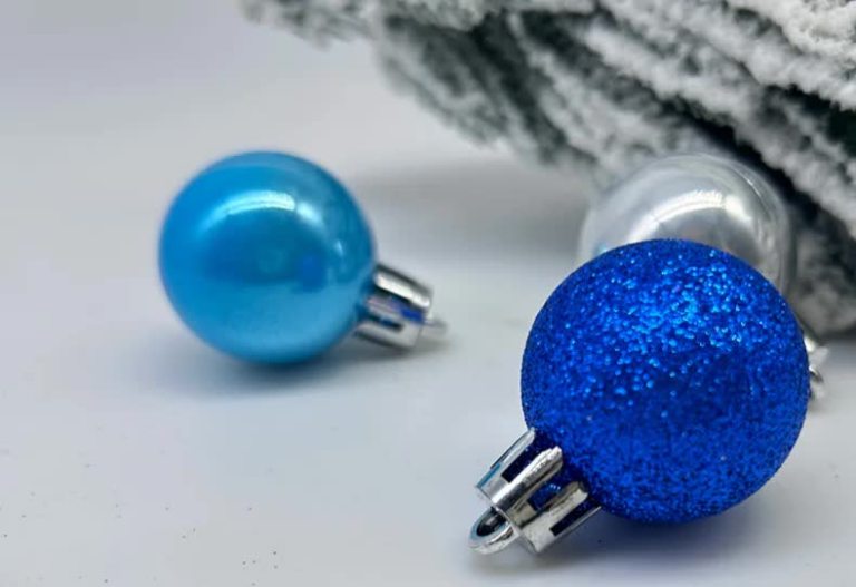 Closeup of blue and silver Christmas baubles on fabric.