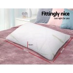 White memory foam pillow with dimensions on bed.