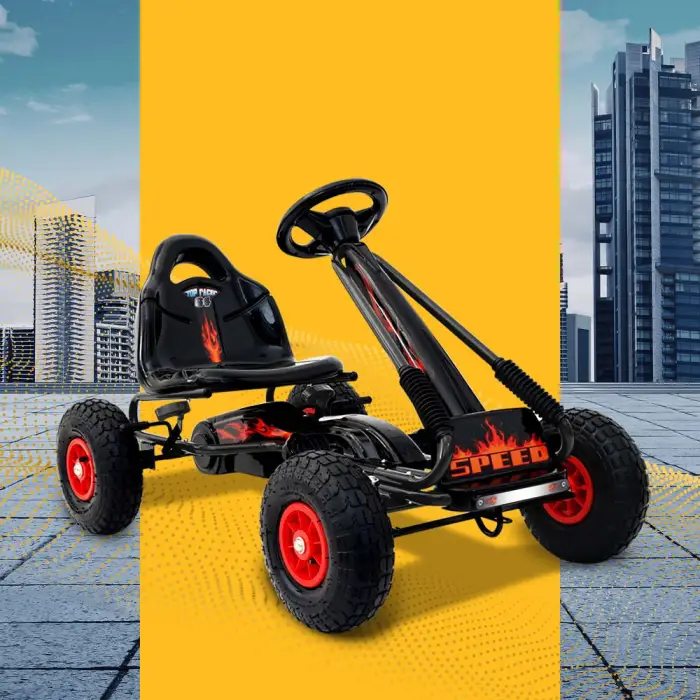 Black pedal go-kart with red wheels in cityscape.