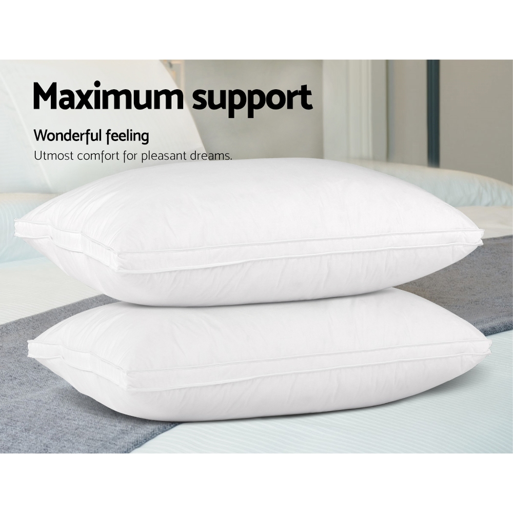 Two stacked white pillows on a bed, maximum support.