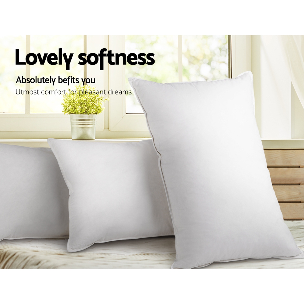 Soft white pillows on a bed near window.