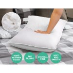Hand pressing feather-filled pillow on bed.