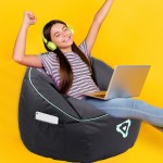 laser gaming bean bag with pocket & headphone strap Happy girl relaxing with laptop, wearing headphones.