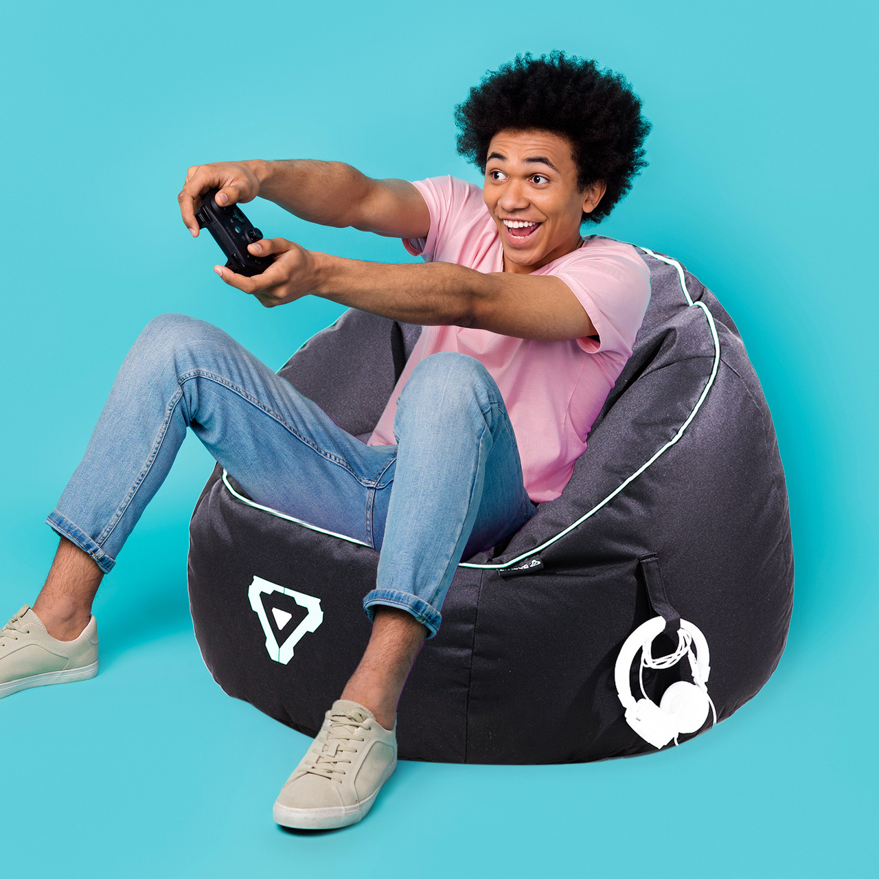 Person gaming on a bean bag, excited expression.