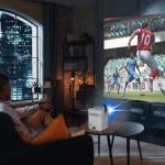 laser cube android projector with 120in screen Man watching football game via projector at home.