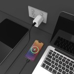 Smartphone charging on desk near laptop and power outlet.