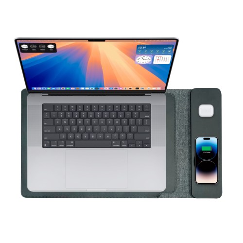 Laptop with smartphone and AirPods on charging pad.