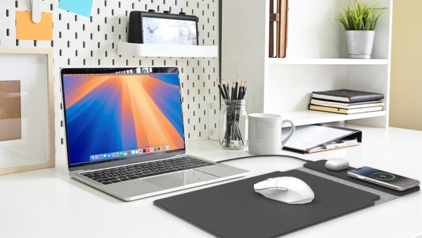 Modern desk with laptop, stationery, and potted plant.