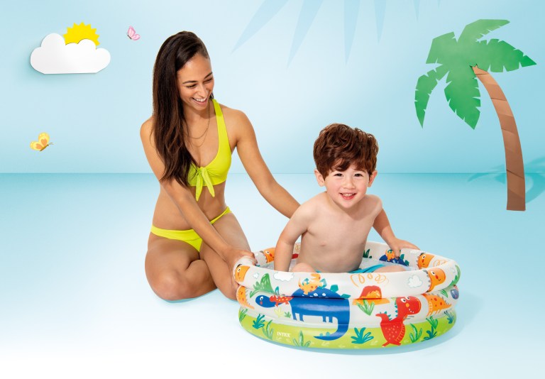 intex dino buddies 3 ring inflatable kiddie pool 57106 Woman and child playing in inflatable pool indoors.