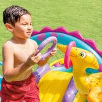 Child playing with inflatable dinosaur in garden