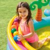 Child playing in colourful inflatable pool with balls.