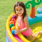 Child playing in colourful inflatable pool with balls.