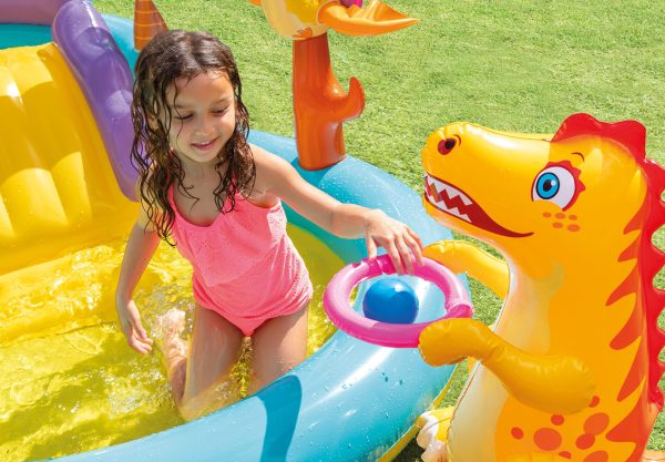 Child playing in inflatable pool with dinosaur toy.