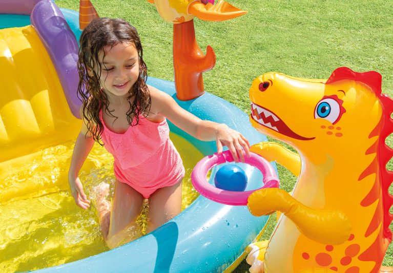 Child playing in inflatable pool with dinosaur toy.