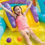 Child enjoying colourful water slide with balls.