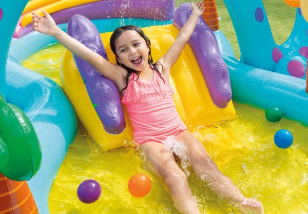 Child enjoying colourful water slide with balls.