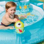 Child playing with toy in inflatable pool.