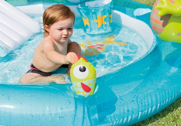 Child playing with toy in inflatable pool.