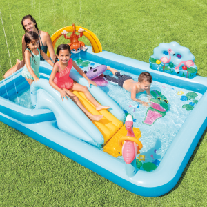 Children playing in inflatable backyard pool with slide.