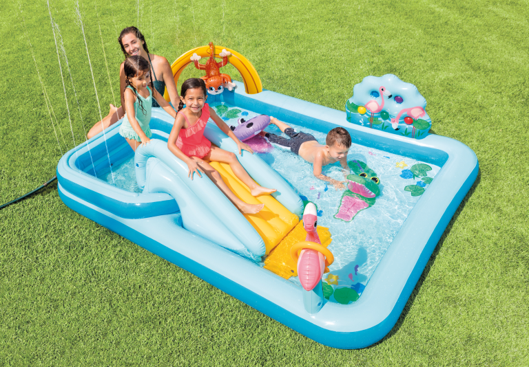 Children playing in inflatable backyard pool with slide.